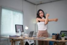 Office worker stretching arms at her desk in the office