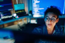 Focused Hispanic female programmer working with code in tech office