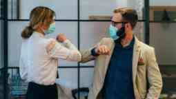 Coworkers doing elbow bump during COVID-19 in an office