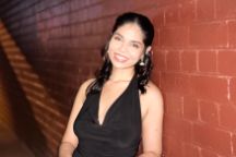 female science student standing at brick wall smiling