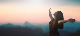 Inspirational woman with arms raised at sunrise, concept of freedom, mental health and hope