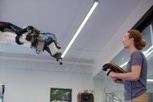 Male student in protolab examining KUKA robotic arm