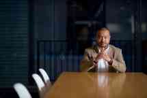 Man sitting at end of table with hands together