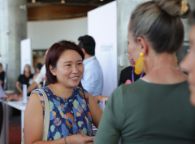 A woman in a blue dress speaks to a Swinburne academic at the Swinburne Study Expo.