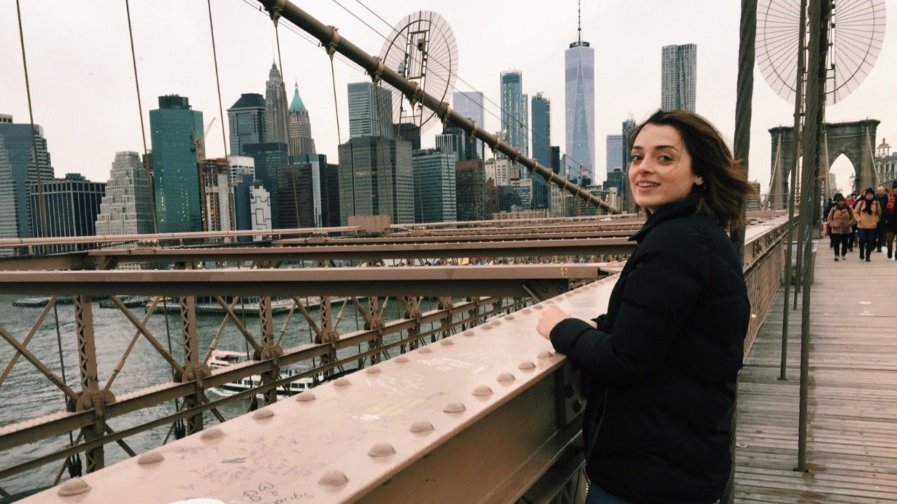 A female Swinburne student on exchange in New York City, on the Brooklyn Bridge overlooking the East River.