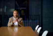 Man sitting at end of table with hands together
