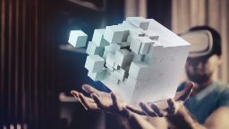 A graphic cube with smaller cubes breaking off on a pair of hands.