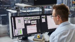 a male looking am multiple screens with different charts and workflows on the screens