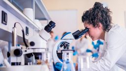 A female student looking into a microscope in a laboratory.