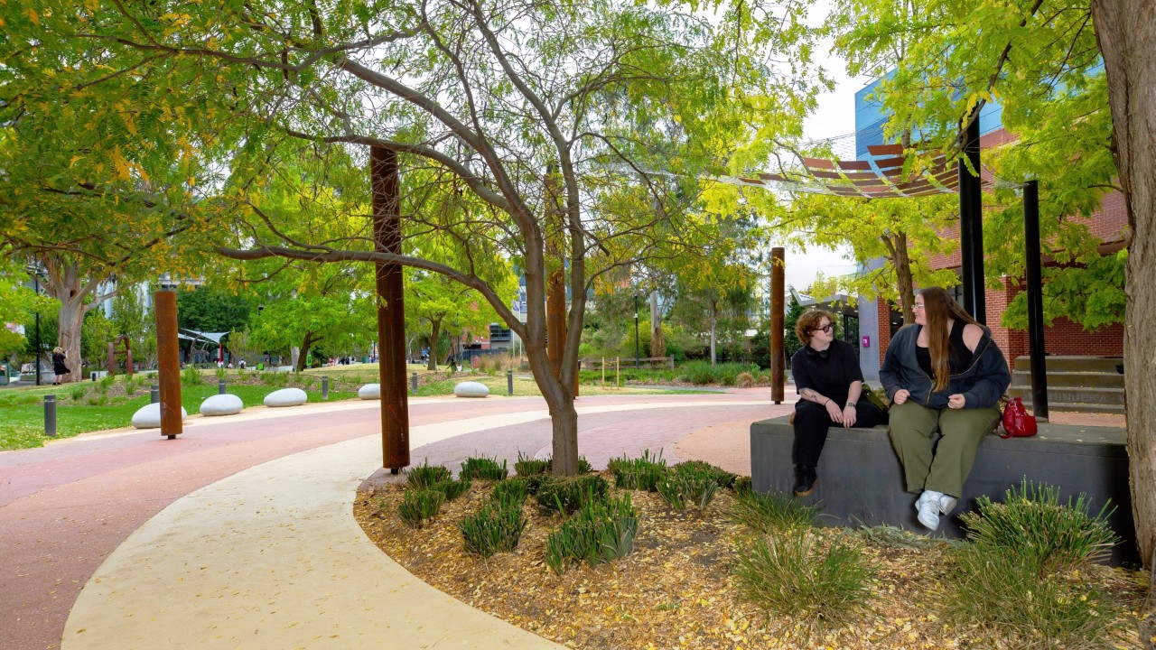 Two students sitting under a tree at the Indigenous Learning Centres on Swinburne's Hawthorn campus.