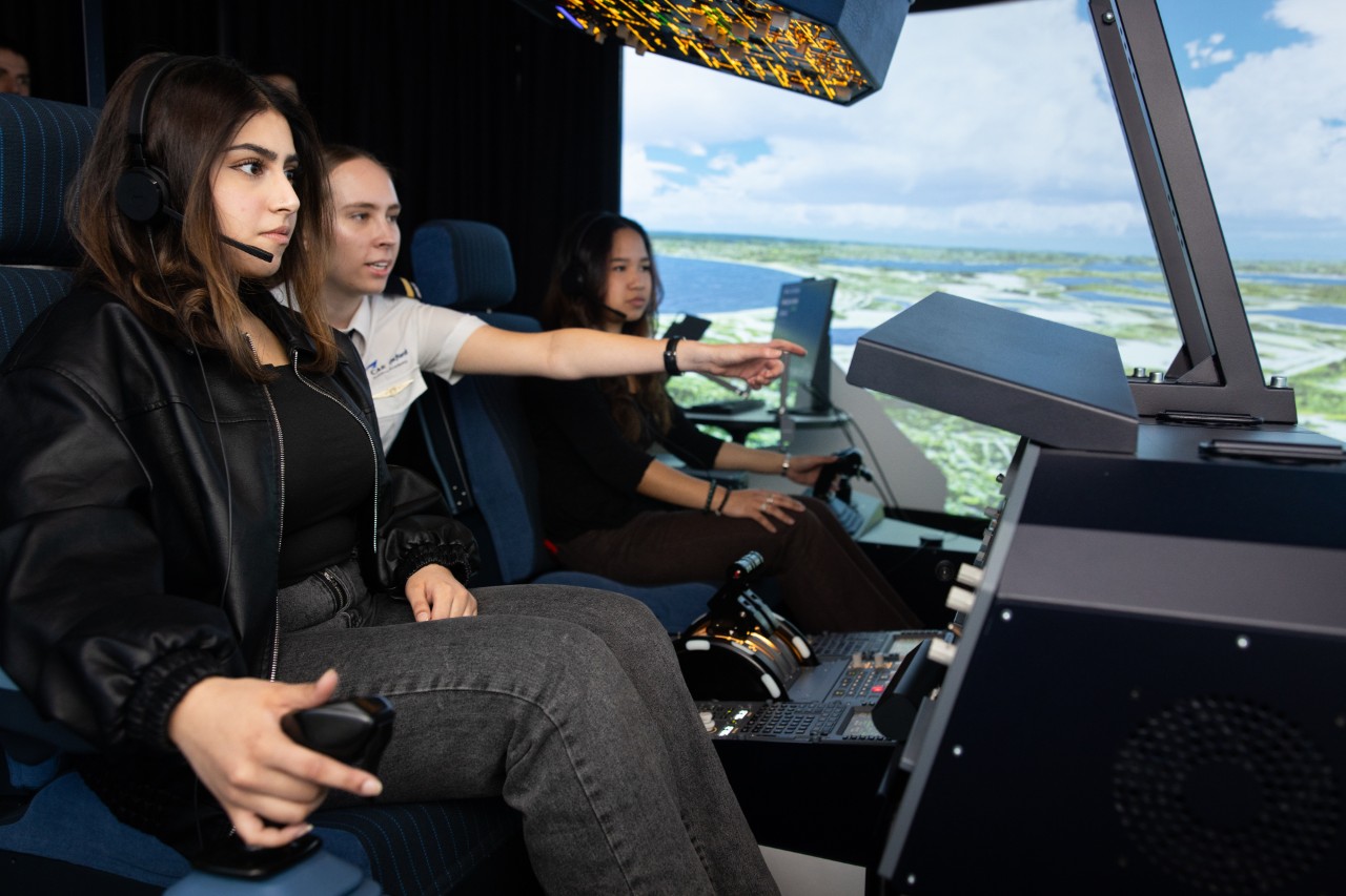 Aviation management students gaining flight deck insights under the guidance of a piloting student for better decision-making on the ground.