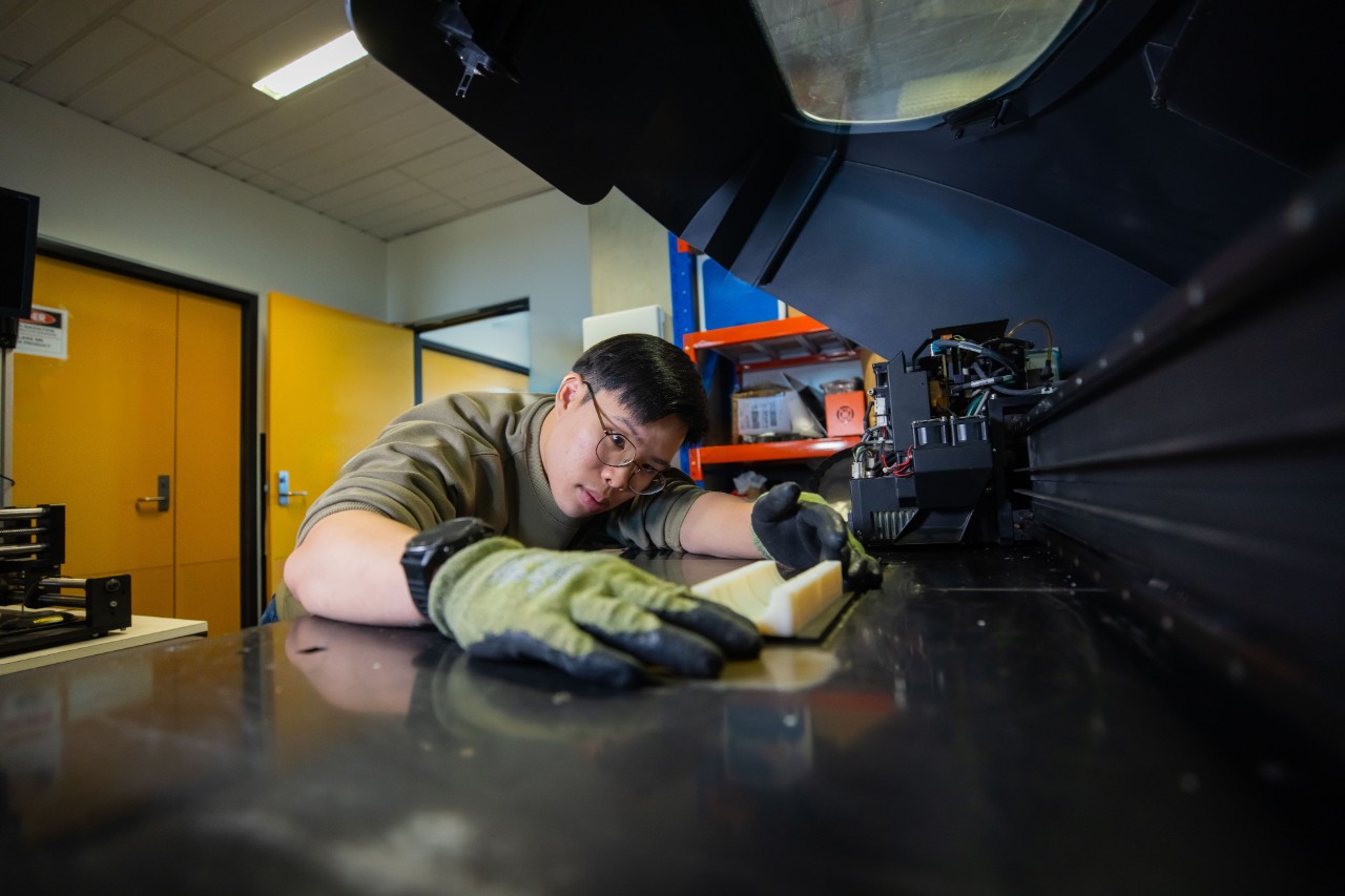 A student using the PolyJet EDEN350 3D printer in the Polymer Processing and Testing Lab.