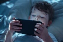 Child Watching Smartphone Screen in Bed at Night