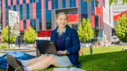 School aged student in uniform sitting on the grass at Hawthorn campus
