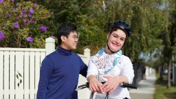 A placement student accompanying a disabled child on a walk outside a house