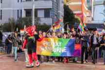 A group with pride rainbow flags walking through a uni campus proudly supporting Swinburne's LGBTQI community.