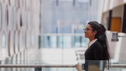 Student wearing glasses with long dark hair walking in ATC building, Hawthorn campus
