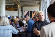 Crowd at Swinburne Study Expo, Hawthorn campus, chatting around tables in a modern hall with concrete pillars and art.