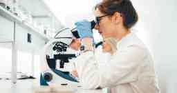 Young scientist looking through microscope in laboratory