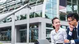 Colleagues sitting outside an office building chatting.