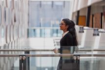 Student with long hair and wearing glasses walking towards a classroom