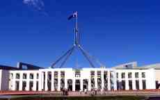 Canberra's Parliment house is a wide white building with columns and a large flag at the top.