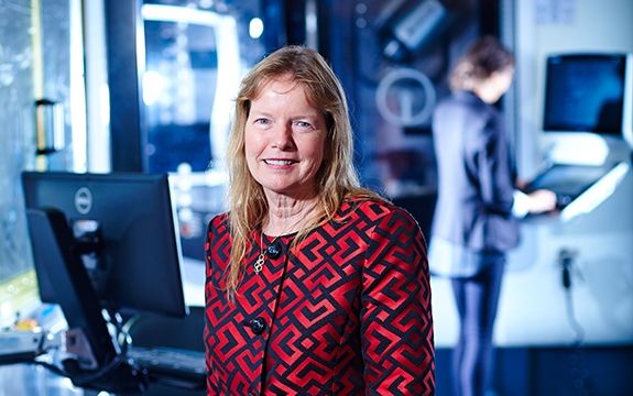 Dr. Leonie Walsh stands in front of blurred science lab equipment