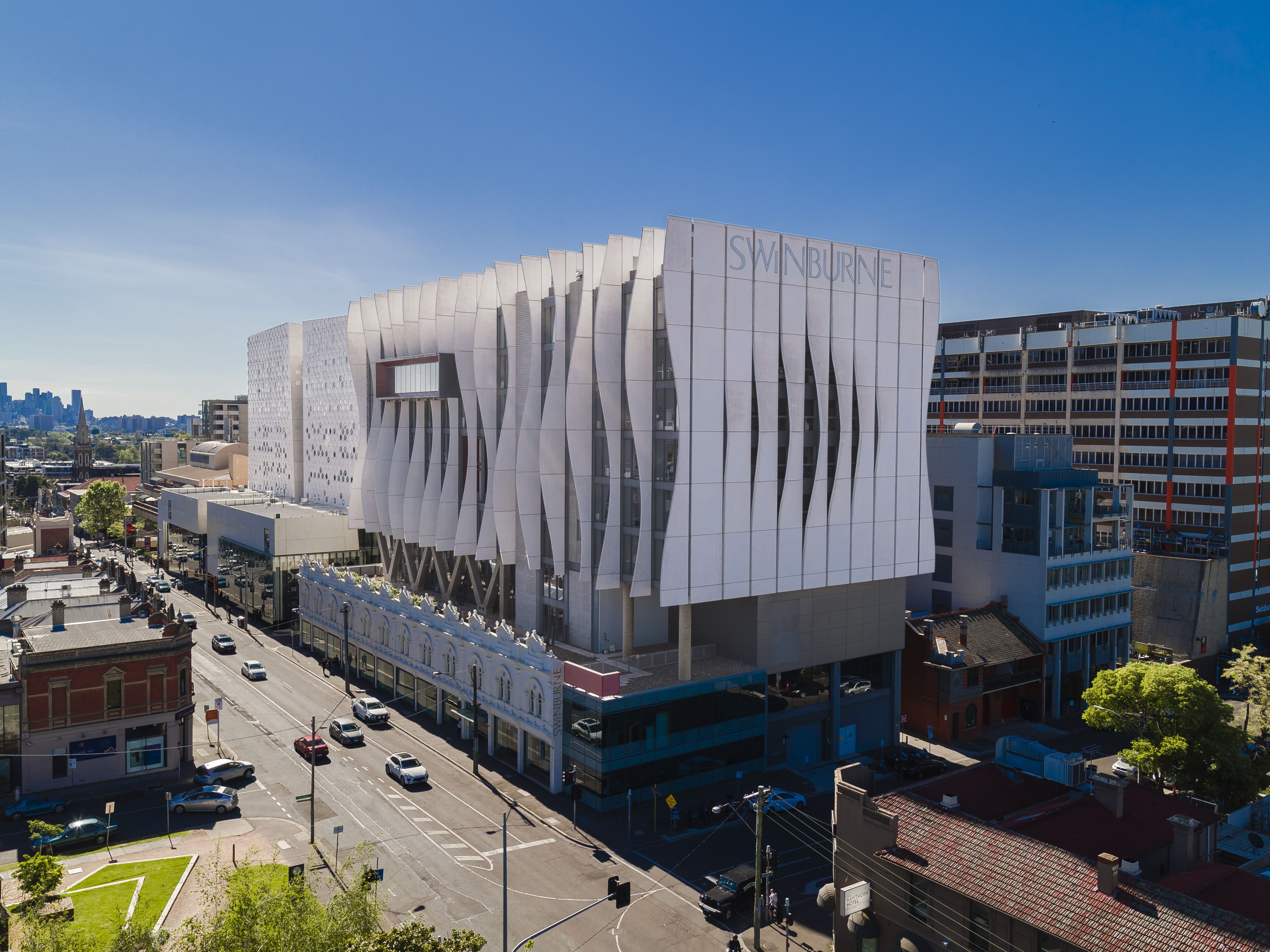 large square white building from high above city in the background blue sky