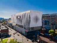large square white building from high above city in the background blue sky