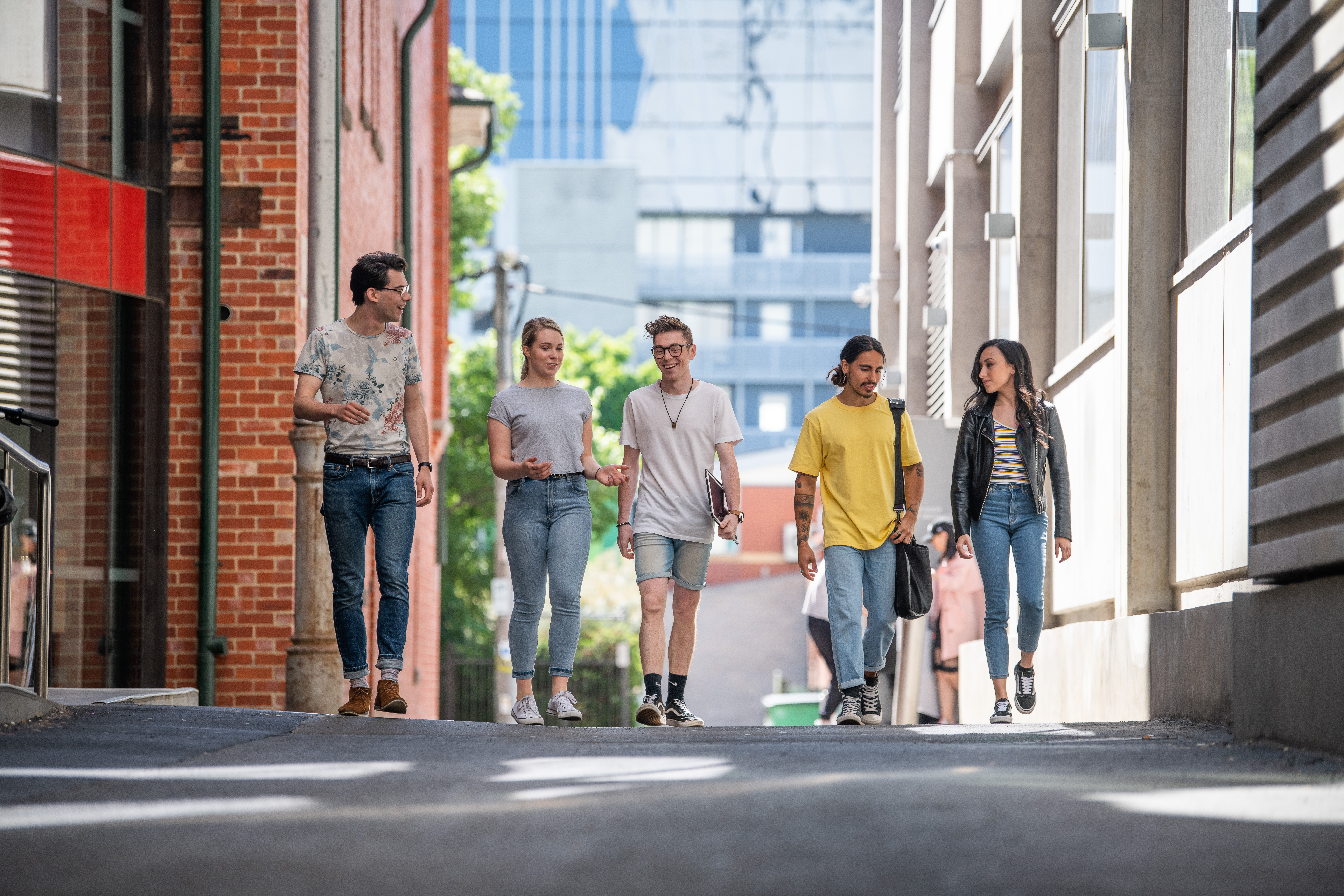 Group of 5 students chatting and walking together down McLeod Lane, between AMDC and FS buildings