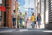 Group of 5 students chatting and walking together down McLeod Lane, between AMDC and FS buildings