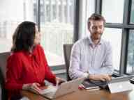 Two people with a laptop and a tablet on a desk