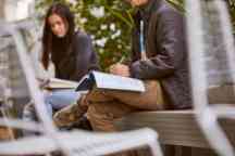 Male and female students sit and work on a book