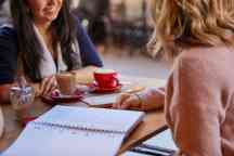 Two female students drink coffee at a cafe in Hawthorn 