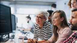 Team of young computer programmers cooperating while working on desktop PC in the office.