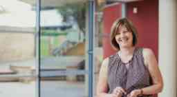 A front-view shot of a cheerful mature businesswoman standing with a smile on her face.