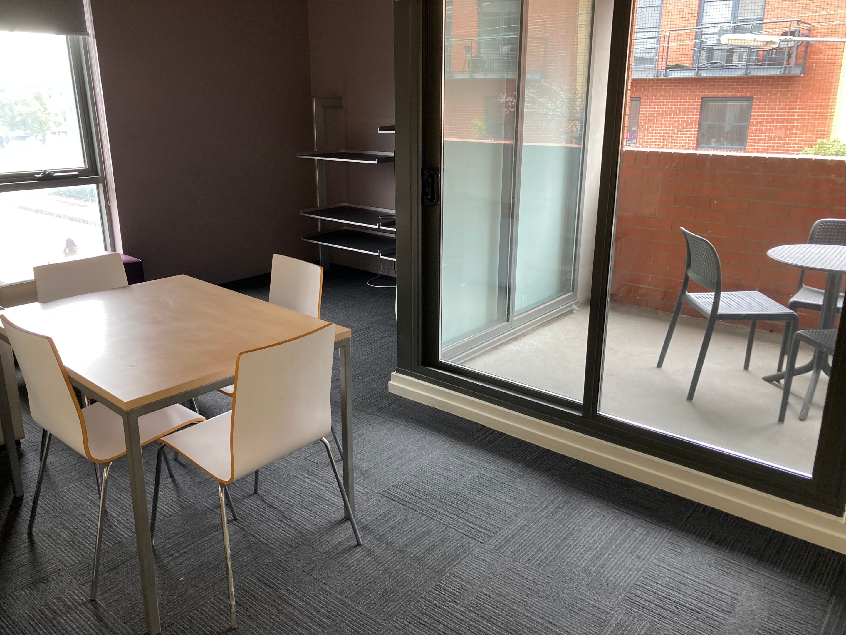 The living room in an apartment at Hawthorn campus with a dining table and four chairs, looking our to the small balcony