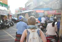 Person carrying a backpack, walking down a busy street.