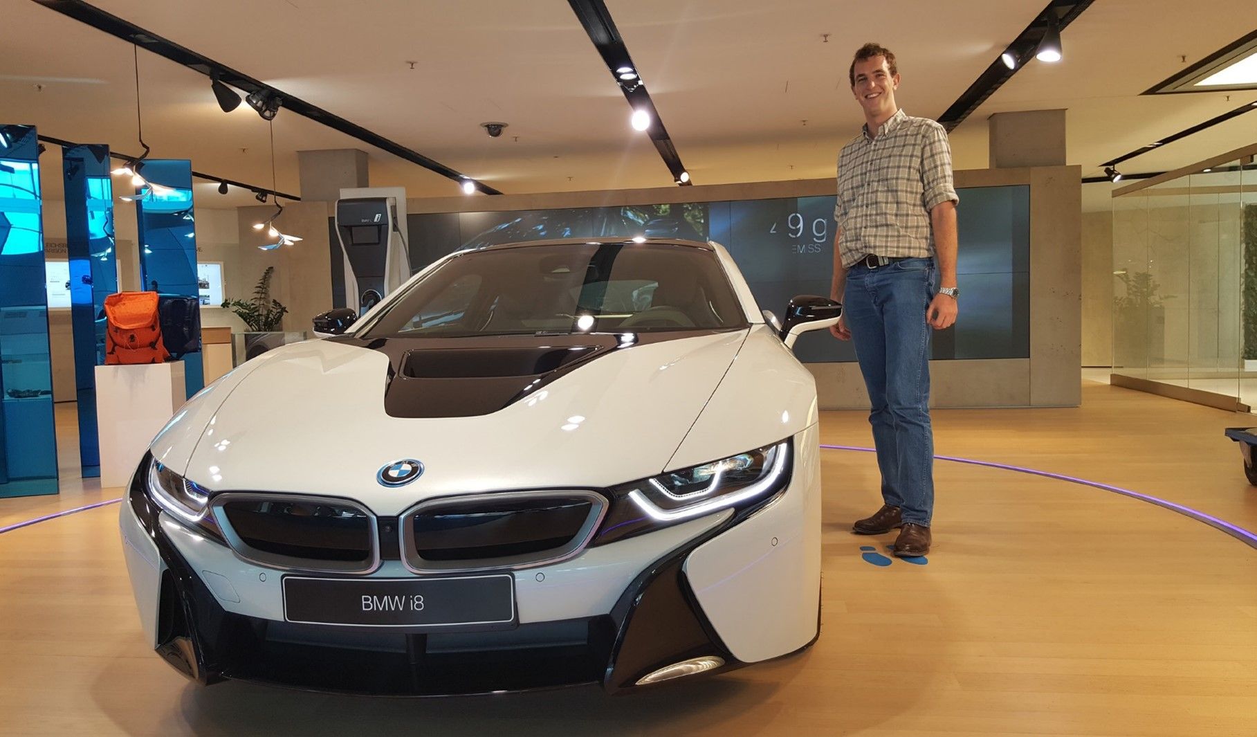 A student interning with BMW standing in front of a car