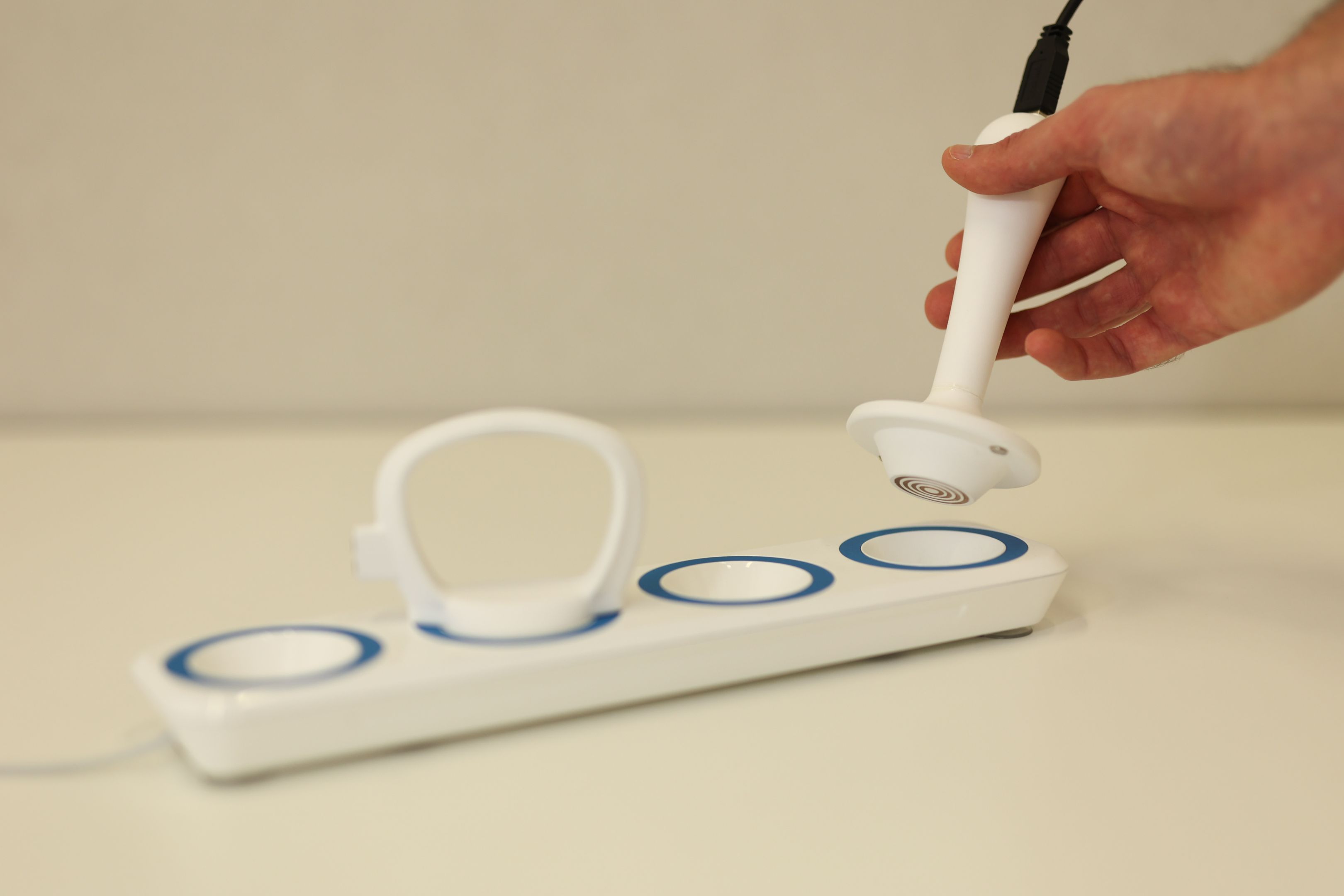 A white ecteronic panel, similar to a socketboard but with circular magnetic connections rather than power sockets. One round grip connection is already plugged in, while someone connects another connection with a sick style grip