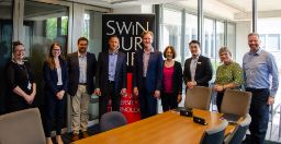 Representatives from Swinburne and BYCA standing behind a Swinburne banner in a meeting room. 