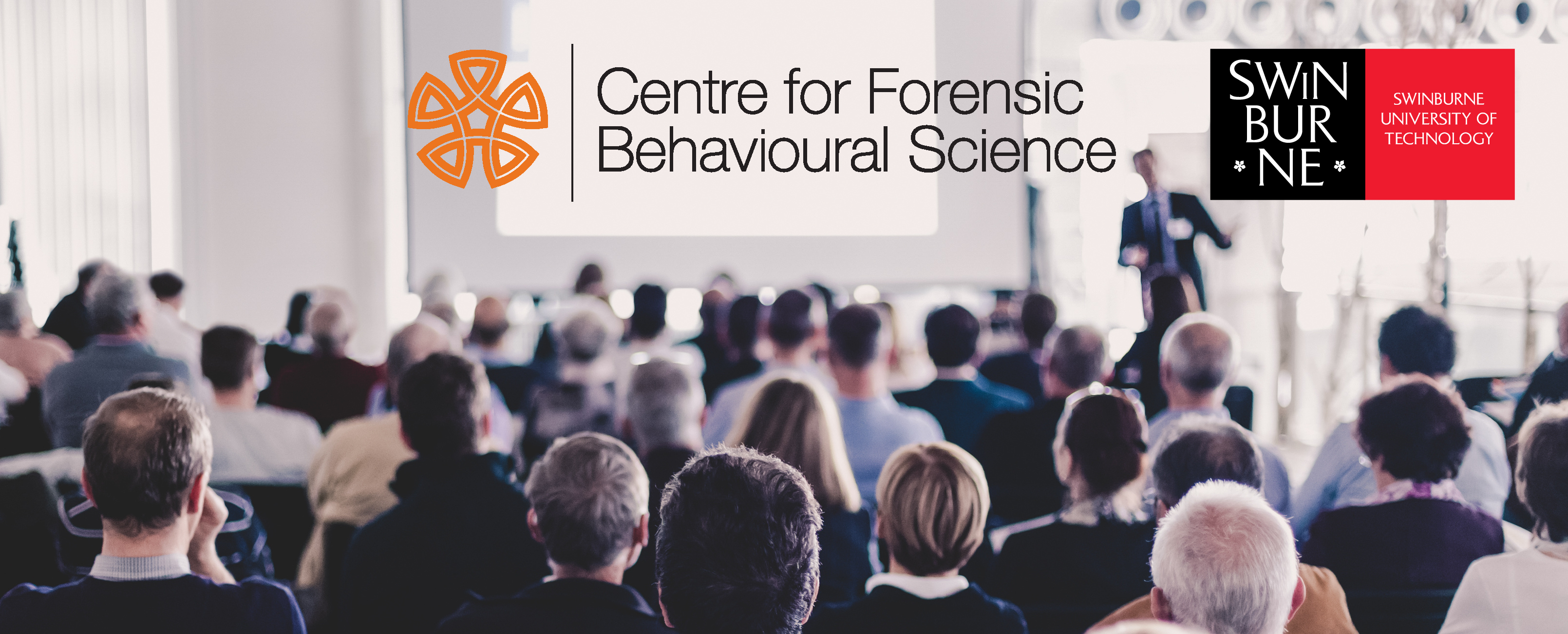 Crowd watching a presentation, viewed from behind the crowd