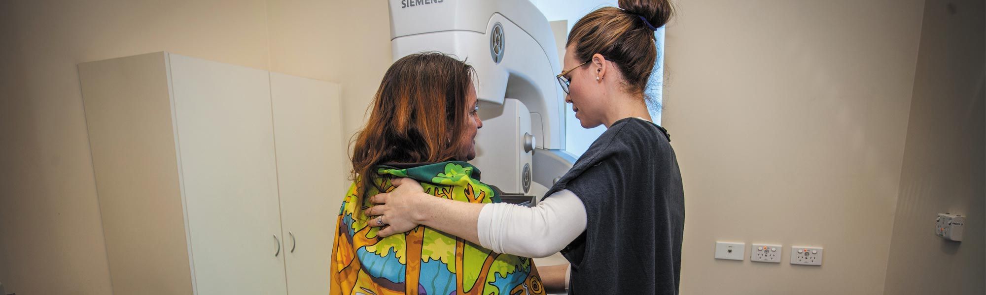 A healthcare professional tends to a woman during a breast screening procedure
