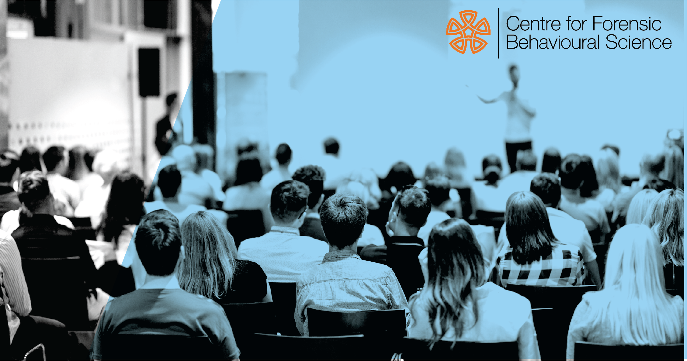 A lecture being delivered with rows of attendees watching a presenter