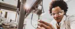 Black female engineer working on industrial machine in a laboratory.