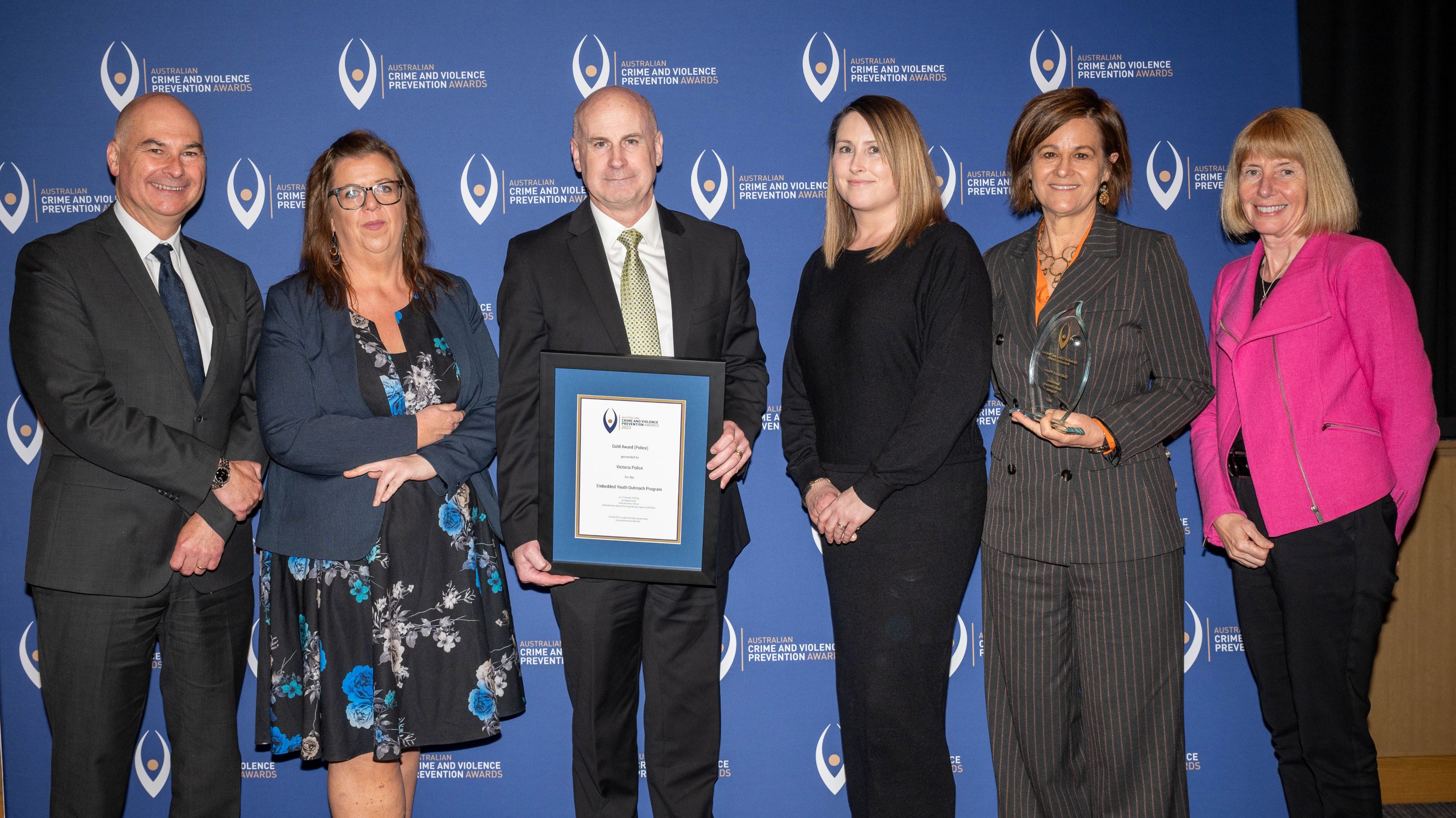Six people posing with award.