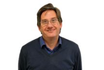 Portrait of a person wearing glasses, smiling slightly.