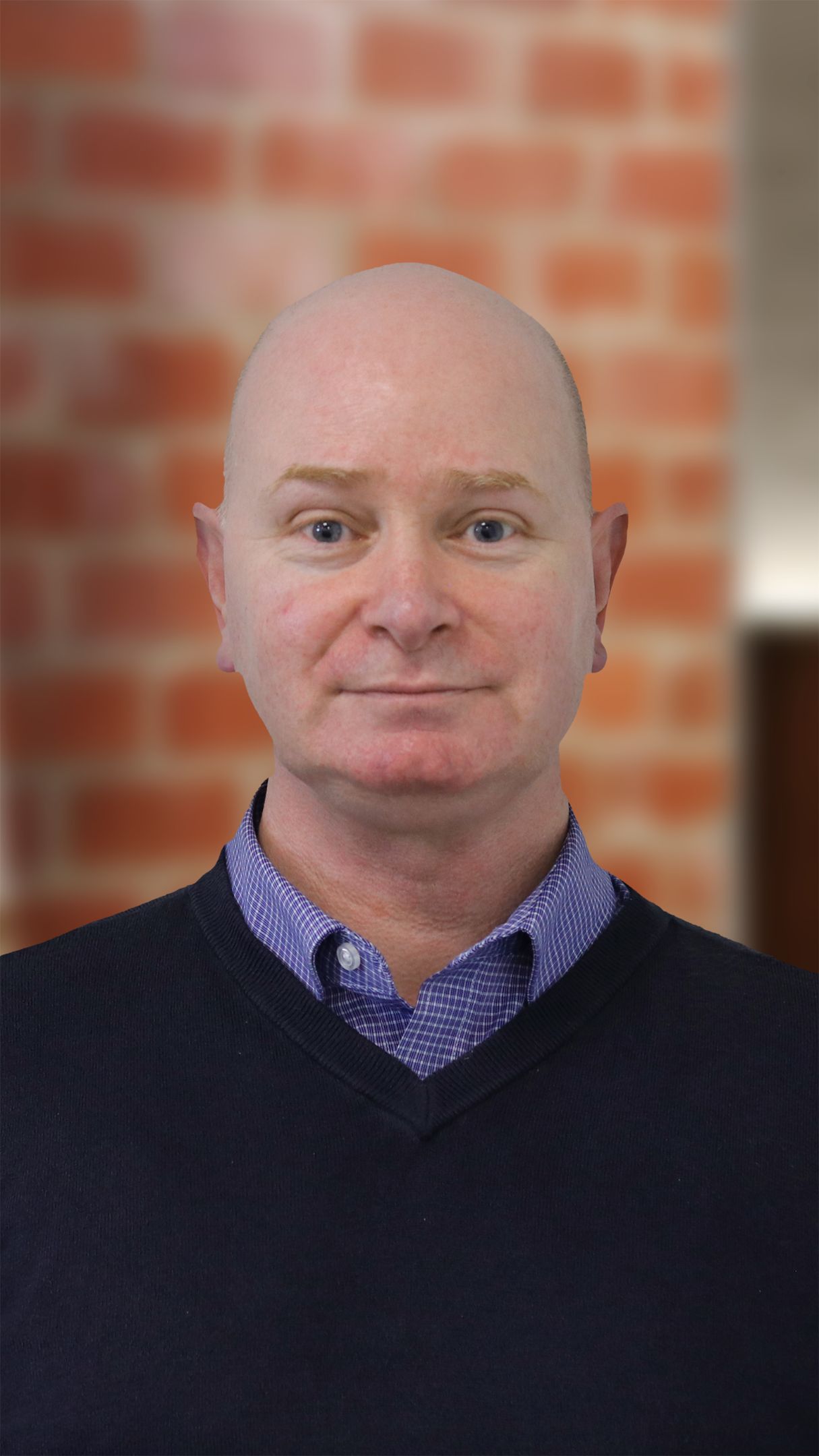 Man wearing a blue jumper, smiling at the camera. 