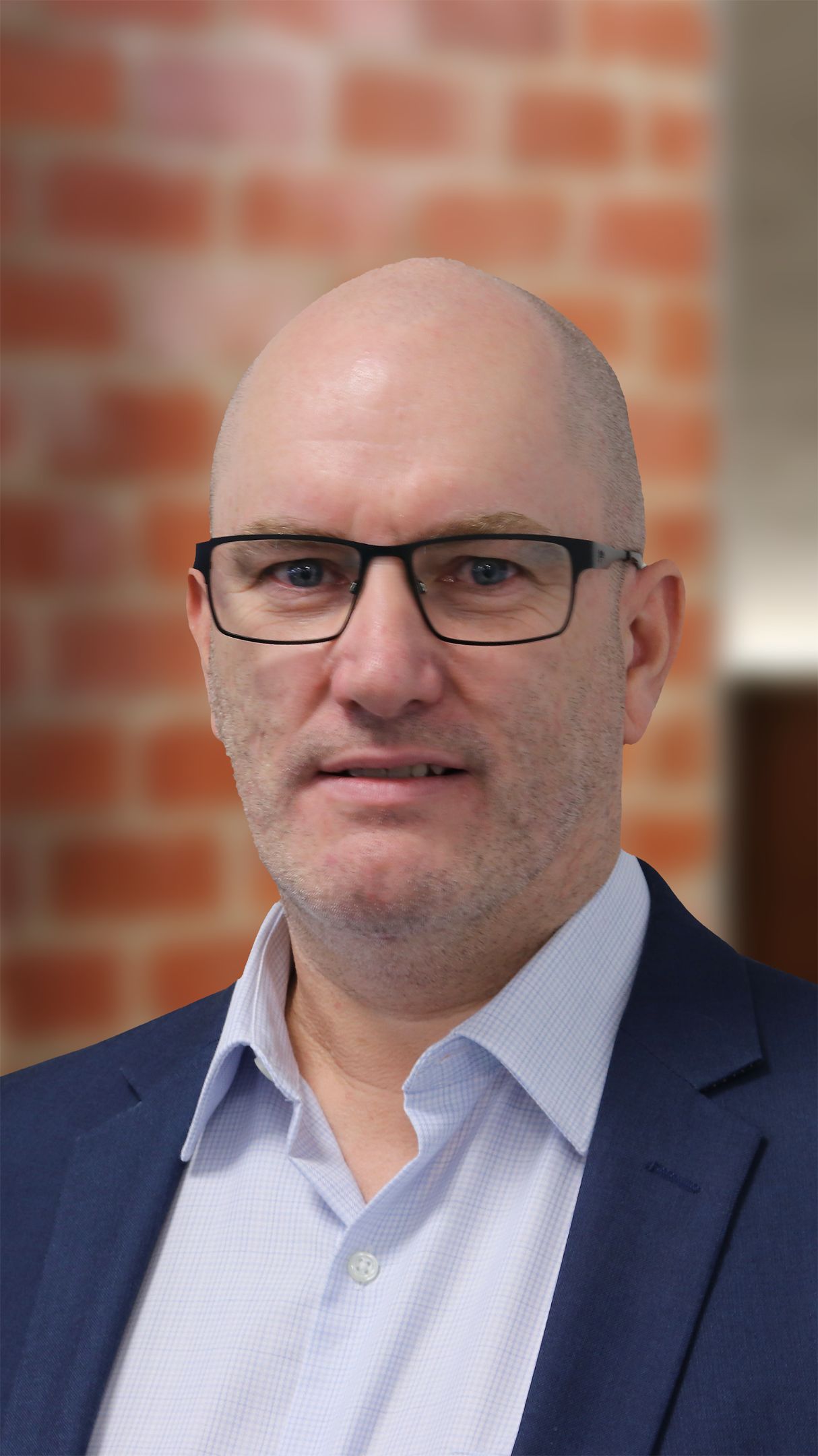 Close up shot of a man with glasses smiling for the camera.
