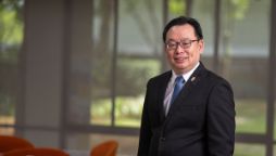 A professional man wearing a suit and glasses, looks to camera. 